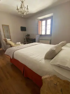 a bedroom with a large bed and a chandelier at As Miguiñas do Cebreiro in Piedrafita