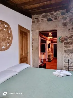 a bedroom with a green bed and a stone wall at Casita Meu Pai in Boimorto