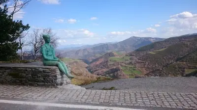 a statue of a woman sitting on a wall looking at the mountains at Casa Antón O Cebreiro in O Cebreiro