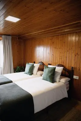 two beds in a room with wooden walls at Casa As Nogueiras in Deade