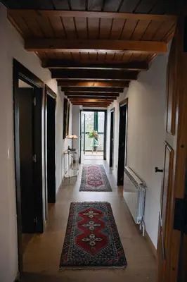 a hallway with rugs on the floor and a ceiling with wooden beams at Casa As Nogueiras in Deade