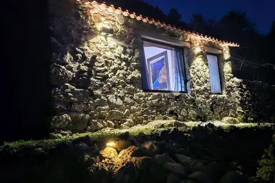a person looking out a window of a stone building at night at cabaña do rei in Betán