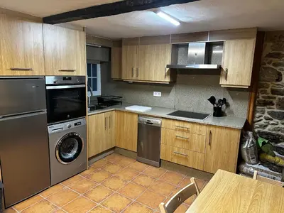 a kitchen with stainless steel appliances and wooden cabinets at A Ribeira in Castro Caldelas