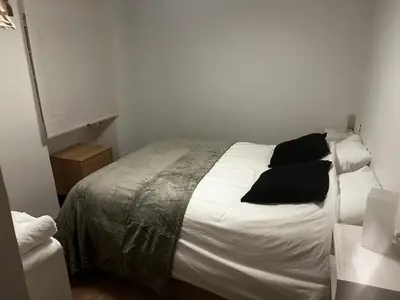 a bedroom with a bed with white sheets and black pillows at A Ribeira in Castro Caldelas