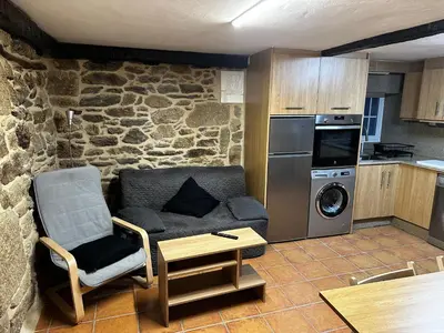 a living room with a couch and a kitchen at A Ribeira in Castro Caldelas