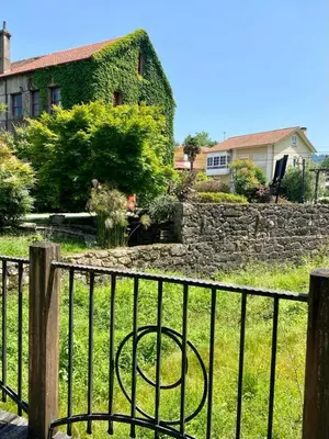 a fence in front of a yard with a house at El Balcón del Eume, Cantina Río Covés in Puentedeume
