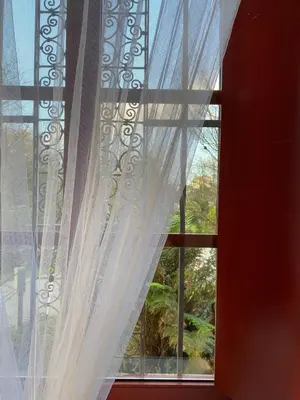 a window with white curtains in a red room at El Balcón del Eume, Cantina Río Covés in Puentedeume