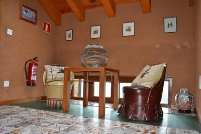 a room with a table and a bird cage and chairs at El Trasgu de Foncebadón in Foncebadón