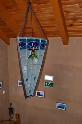 a stained glass chandelier hanging from a ceiling with pictures at El Trasgu de Foncebadón in Foncebadón
