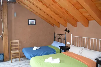 two twin beds in a room with wooden ceilings at El Trasgu de Foncebadón in Foncebadón