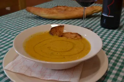a bowl of soup on a table with a glass of wine at El Trasgu de Foncebadón in Foncebadón