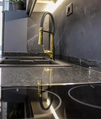 a kitchen sink with a gold faucet on a counter at Golden Home in Ourense