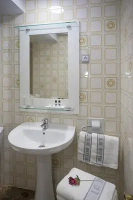 a bathroom with a sink and a mirror and towels at Hotel La Ruta in Tapia de Casariego