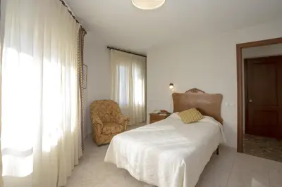 a bedroom with a bed and a chair and a window at Hotel La Ruta in Tapia de Casariego