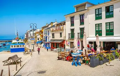 a group of buildings with tables and chairs near the water at Hotel La Ruta in Tapia de Casariego