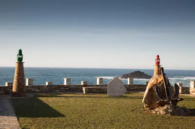 a rock and two light posts next to the ocean at Hotel La Ruta in Tapia de Casariego