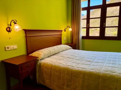 a bedroom with a bed with blue walls and a window at Casas Rurales Las Corradas in Éndriga