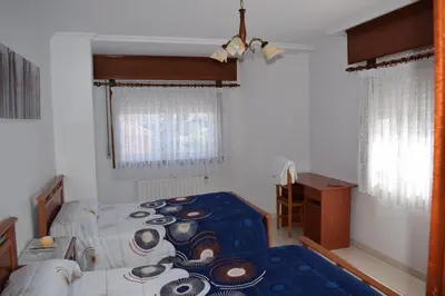 a bedroom with two beds and a table and a desk at El Molino in Melide