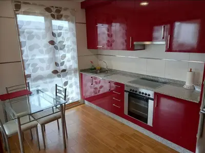 a kitchen with red cabinets and a glass table at Dúplex Entero en Foz in Foz