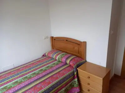 a bedroom with a bed and a wooden night stand at Dúplex Entero en Foz in Foz