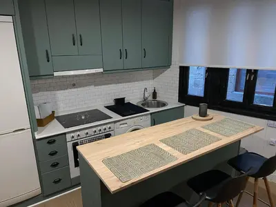 a kitchen with green cabinets and a wooden counter top at Casa Arroio - Casco antiguo de Allariz in Allariz