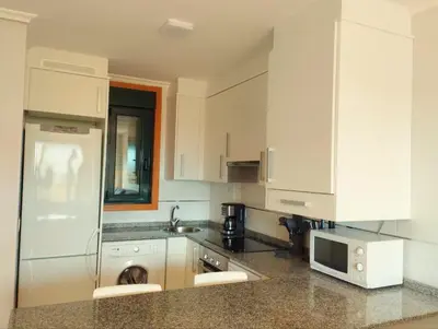 a kitchen with white cabinets and a refrigerator at Costa SPA Terraza de lujo - Playa las Catedrales in San Miguel de Reinante