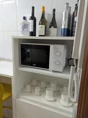 a cabinet with a microwave and cups and bottles of wine at O Pisiño de Andrés in Caldas de Reis