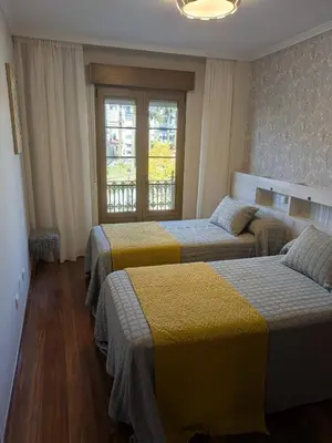 two beds in a room with two windows at O Pisiño de Andrés in Caldas de Reis