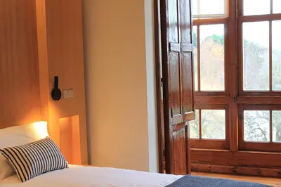 a bedroom with a bed with a door and a window at Hotel Miralrio Cacabelos in Cacabelos