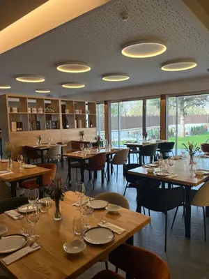 a restaurant with wooden tables and chairs and windows at Hotel Miralrio Cacabelos in Cacabelos