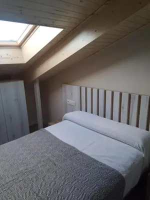 a bedroom with a large bed with a skylight at O Lar do Rodrigo in Castro Caldelas
