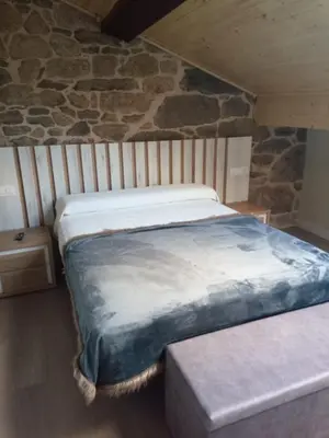 a bedroom with two beds and a stone wall at O Lar do Rodrigo in Castro Caldelas