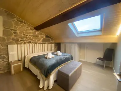 a bedroom with a large bed with a skylight at O Lar do Rodrigo in Castro Caldelas