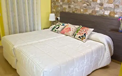 a white bed with pillows on it in a bedroom at Aire de Sanabria in El Puente