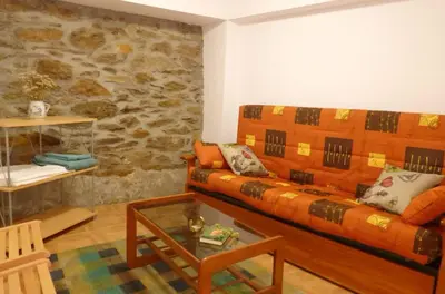 a living room with a couch and a stone wall at Casa en la Ribeira Sacra, Pombeiro in Lago