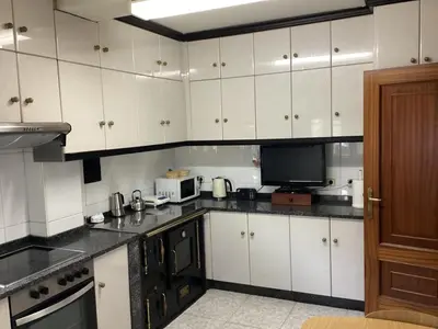 a kitchen with white cabinets and a tv in it at Casa Cancelas in Santiago de Compostela