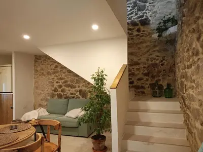 a living room with a green couch and stairs at Ao Carón do Camiño in Padrón