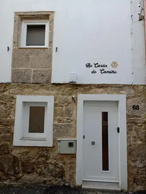 a building with a white door and two windows at Ao Carón do Camiño in Padrón