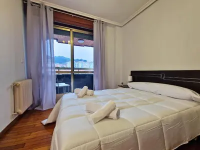 a bedroom with a large white bed with a large window at YourHouse Progreso 1 apartment in Ourense