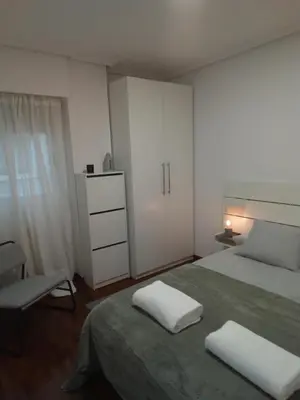 a bedroom with a bed with white cabinets and a chair at A Pia da Moura in Ourense