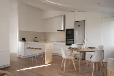 a kitchen with a table and chairs and a kitchen with white cabinets at Avós Apartamentos in Monforte de Lemos