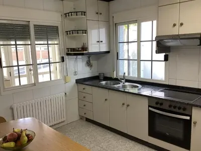 a kitchen with white cabinets and a bowl of fruit on a table at Casa Filomena in Santiago de Compostela