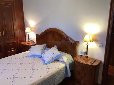 a bedroom with a bed with blue pillows and two lamps at Casa Filomena in Santiago de Compostela