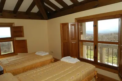 a bedroom with two beds and a large window at Alojamiento Rural El atardecer de Sanabria in San Juan de la Cuesta