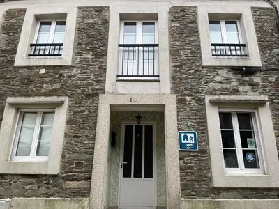 a stone building with a door and four windows at Albergue Amodiño in Arzúa
