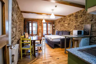 a kitchen and living room with a table and a bed at Alda Fogar Natural in Santiago de Compostela