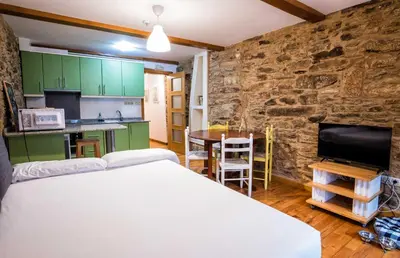 a bedroom with a bed and a stone wall at Alda Fogar Natural in Santiago de Compostela