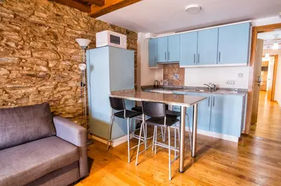 a kitchen with a bar and a couch in a room at Alda Fogar Natural in Santiago de Compostela