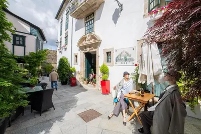 a group of people sitting at a table outside a building at Hotel Monumento Pazo de Orbán in Lugo