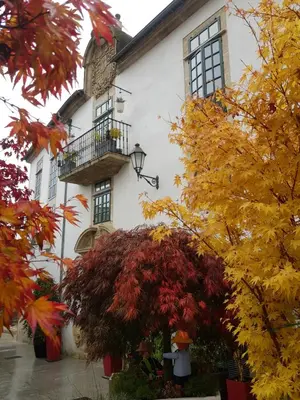 a white building with a balcony and autumn leaves at Hotel Monumento Pazo de Orbán in Lugo